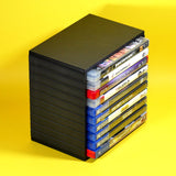 A black plastic game case organizer holding multiple PlayStation 3 game cases, set against a solid bright yellow background.