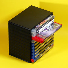 A black PlayStation 3 console with several game cases partially pulled out from the front, set against a bright yellow background.