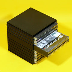 A stack of black plastic CD cases with several discs pulled out from the right side, including a visible PlayStation case, set against a bright yellow background.