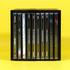A black plastic multi-disc game case holding multiple PlayStation game discs, photographed against a bright yellow background. Visible game titles include Predator, The Nighthawk, Final Fantasy VII, Final Fantasy VIII, Einhänder, Bushido Blade, Striscart, and Diablo.